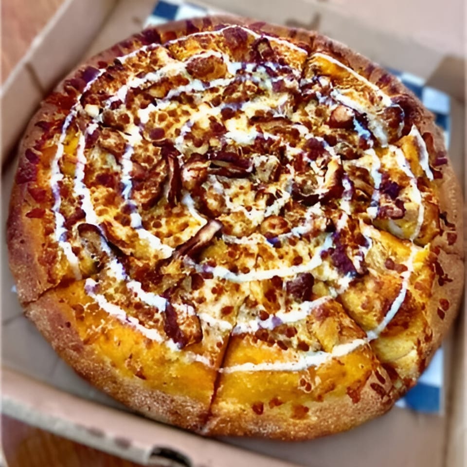 A whole BBQ chicken pizza from The Last Slice, with white sauce swirls, in a delivery box.